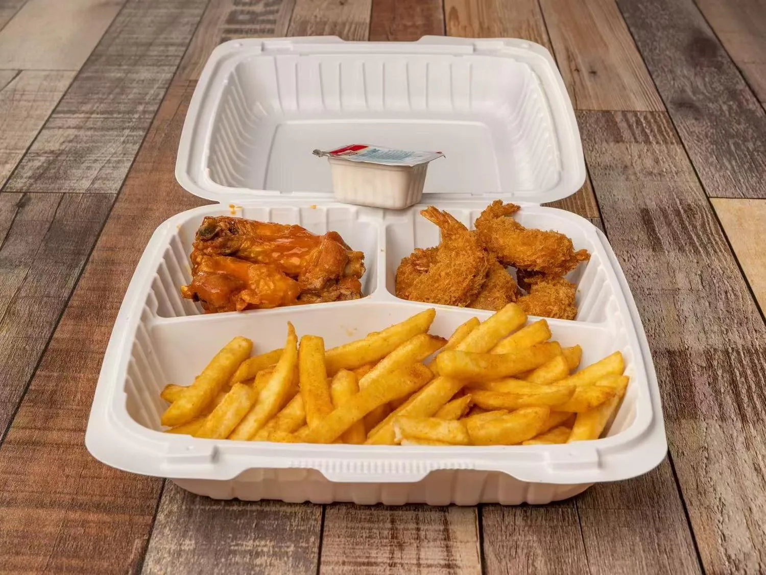 Takeout box with chicken wings fried shrimp and french fries at Aaron Wings & Hibachi, a Hibachi & Wings Restaurant in Stockbridge