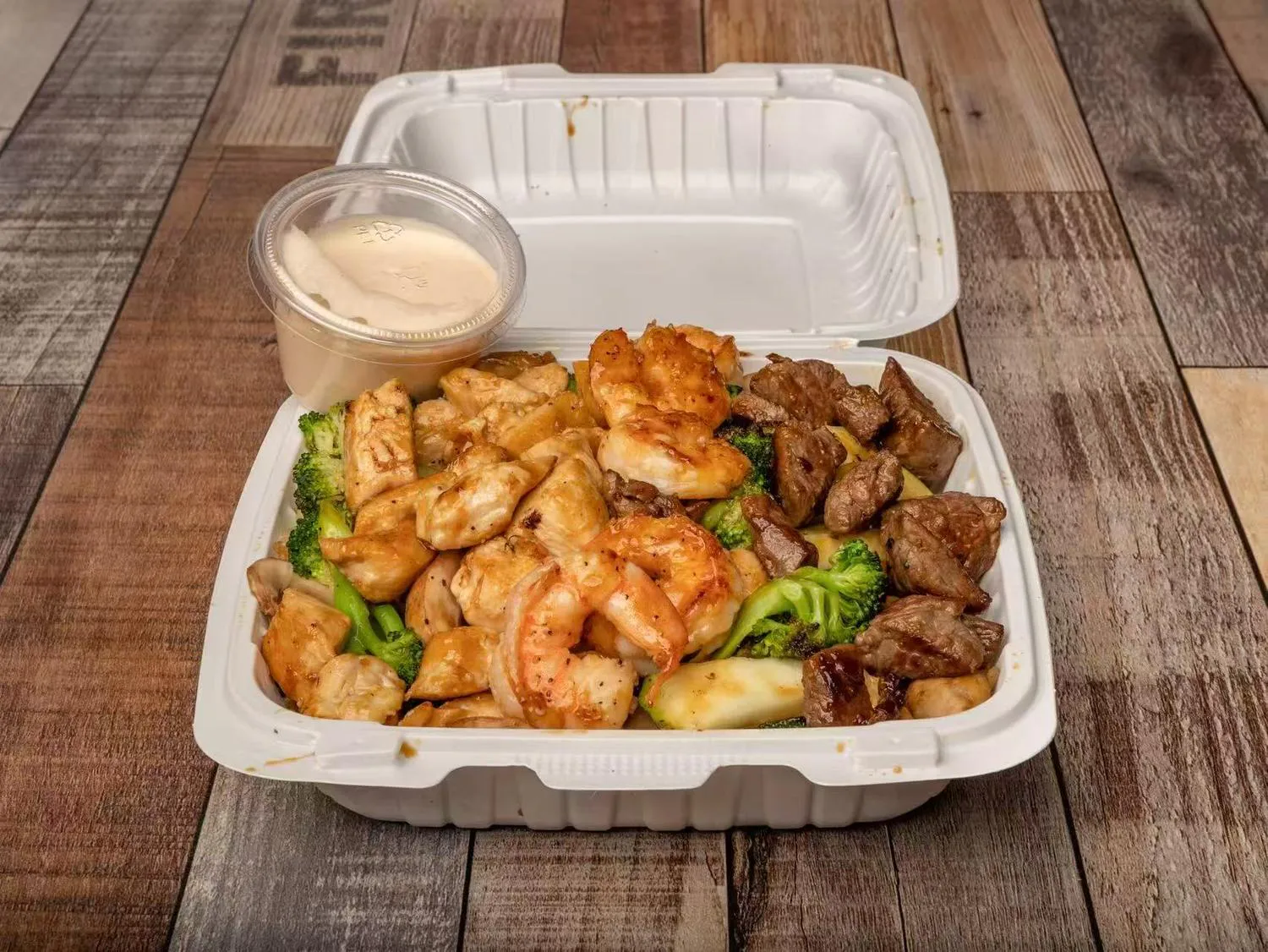 Grilled chicken shrimp and beef hibachi combo with vegetables and sauce at Aaron Wings & Hibachi, a Hibachi & Wings Restaurant in Stockbridge